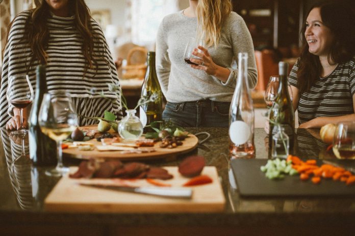 Photo by Kelsey Chance two woman standing beside woman sitting in front of table