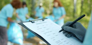 Person in gloves writing on clipboard during cleanup event