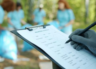 The Real Cost Drivers Behind a Phase I Environmental Site Assessment Person in gloves writing on clipboard during cleanup event