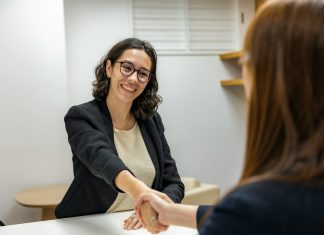 How to Change Careers Without Wasting the Education You Already Have a woman shaking hands with another woman sitting at a table