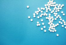 a pile of white pills sitting on top of a blue table