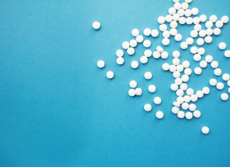 a pile of white pills sitting on top of a blue table