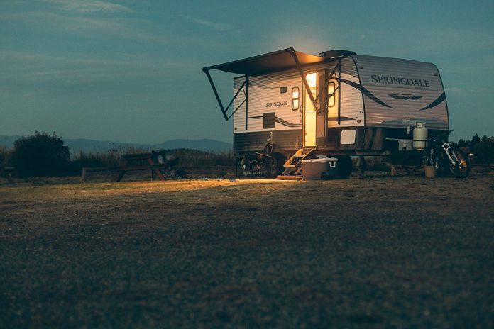 Photo by Devon MacKay a small camper sits in a field at night