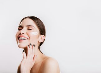 A woman smiles while she holds her hand to her face