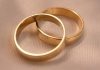 The Power of Simplicity in Classic Wedding Band Design Two interlocking gold wedding bands on a textured cream fabric surface